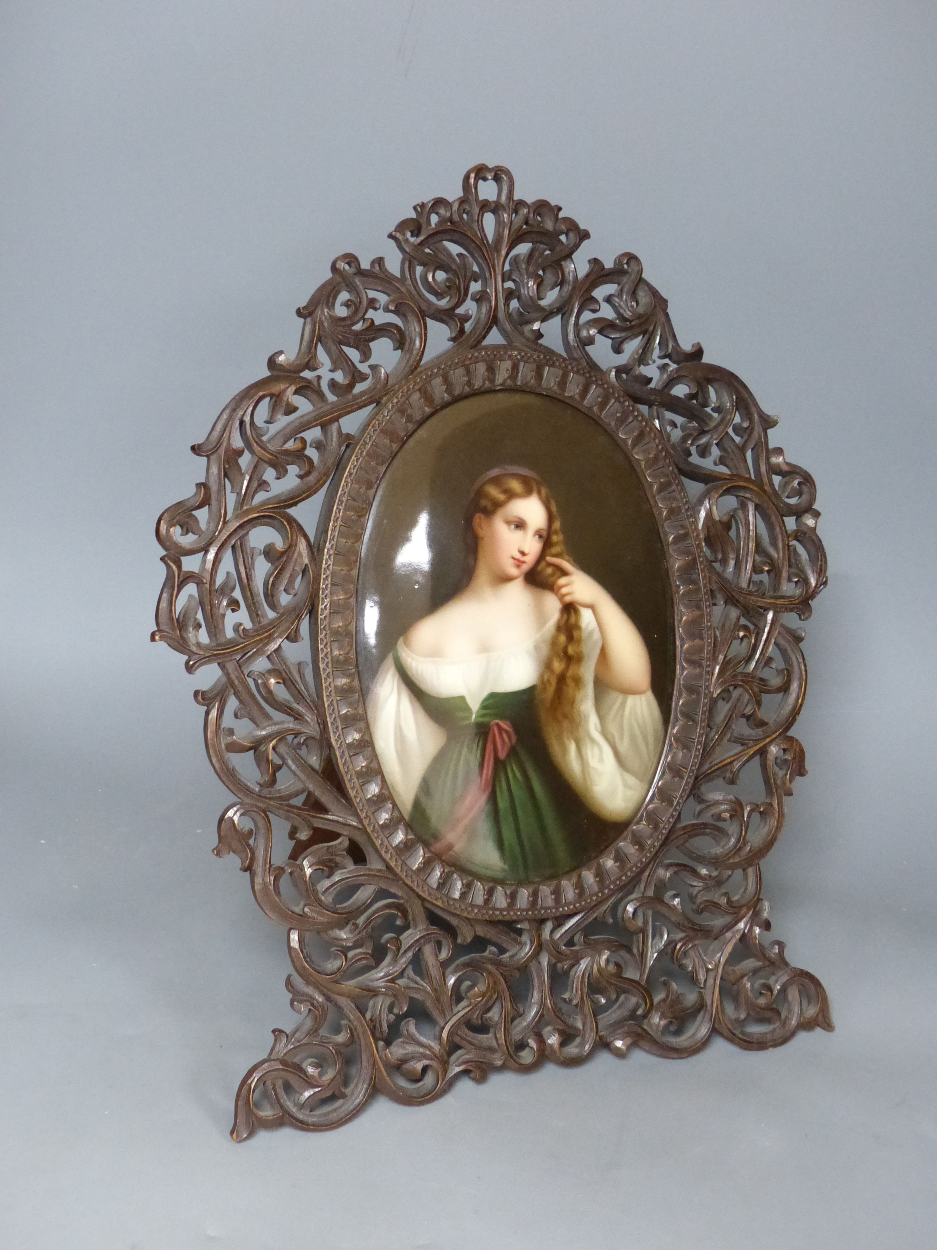 A large 19th century painted Paris porcelain plaque of a girl in a Black Forest carved frame, height 44cm overall